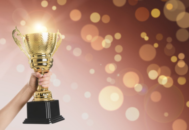 Image of Woman holding gold trophy cup on color background, closeup. Space for text