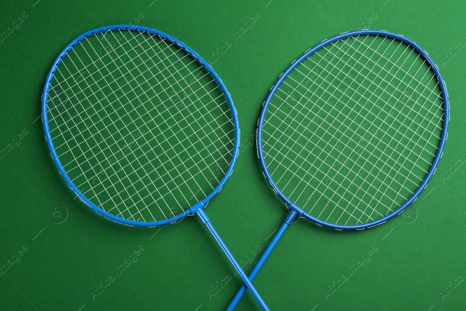 Photo of Badminton rackets on green background, flat lay