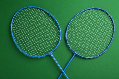 Photo of Badminton rackets on green background, flat lay