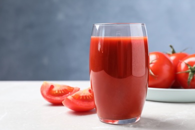 Delicious fresh tomato juice on light grey marble table table, closeup. Space for text