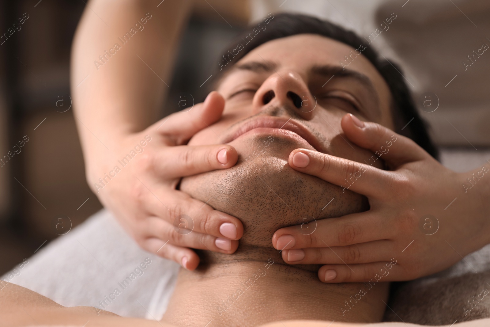 Photo of Man receiving facial massage in beauty salon, closeup