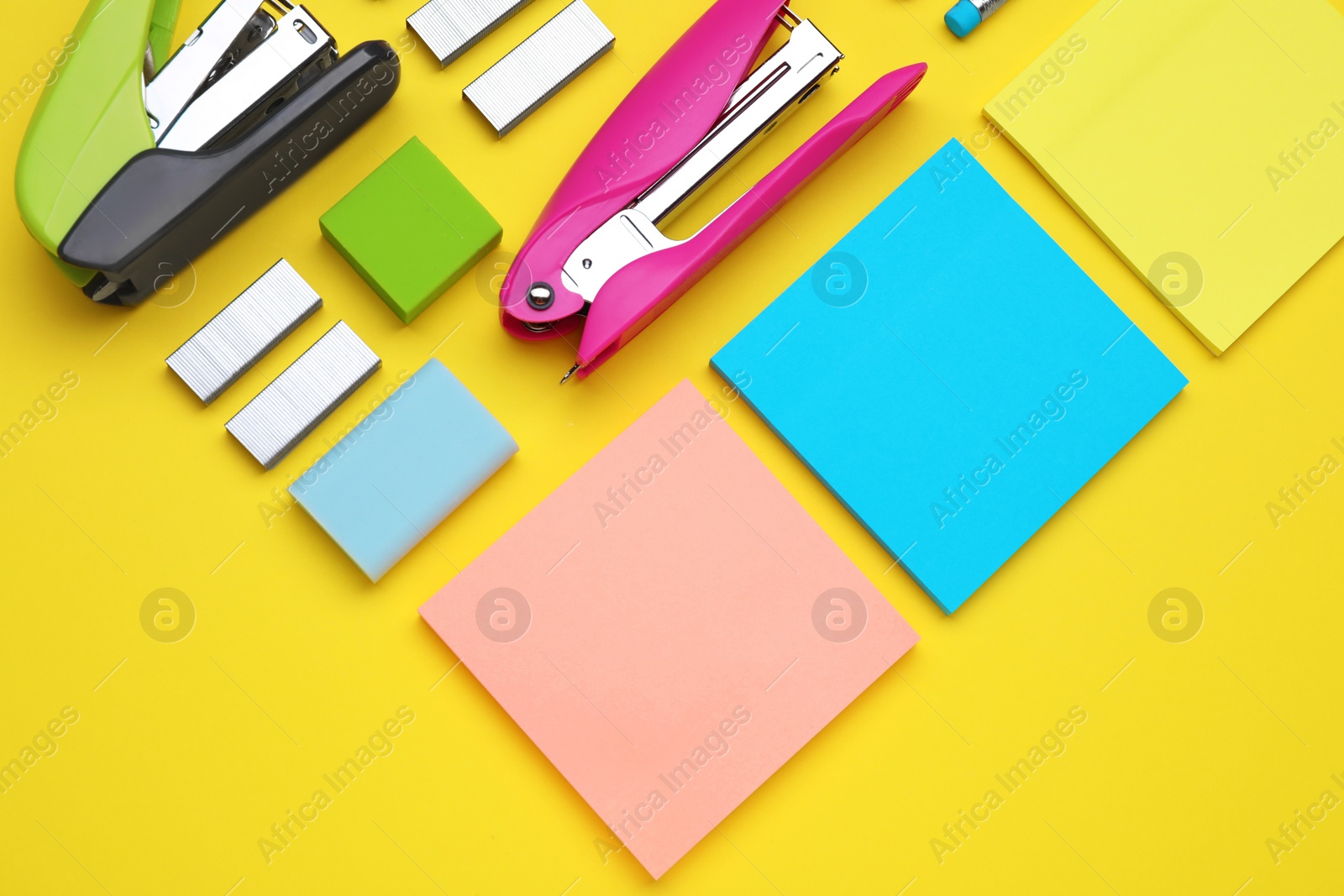 Photo of Flat lay composition with new staplers on yellow background