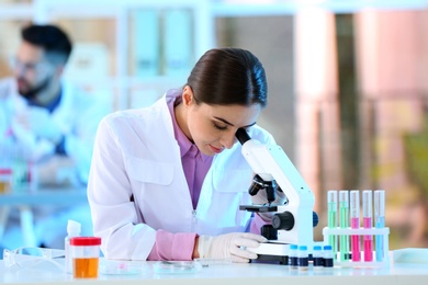 Young scientist working with microscope in laboratory. Chemical analysis