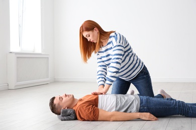 Photo of Woman practicing first aid on unconscious man indoors