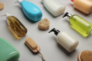 Photo of Many bottles of liquid soap, brushes and luffa on grey background