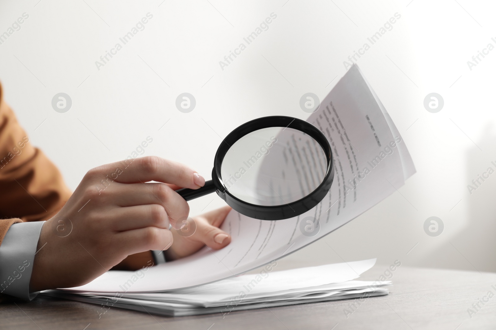 Photo of Woman looking at document through magnifier at table, closeup. Searching concept