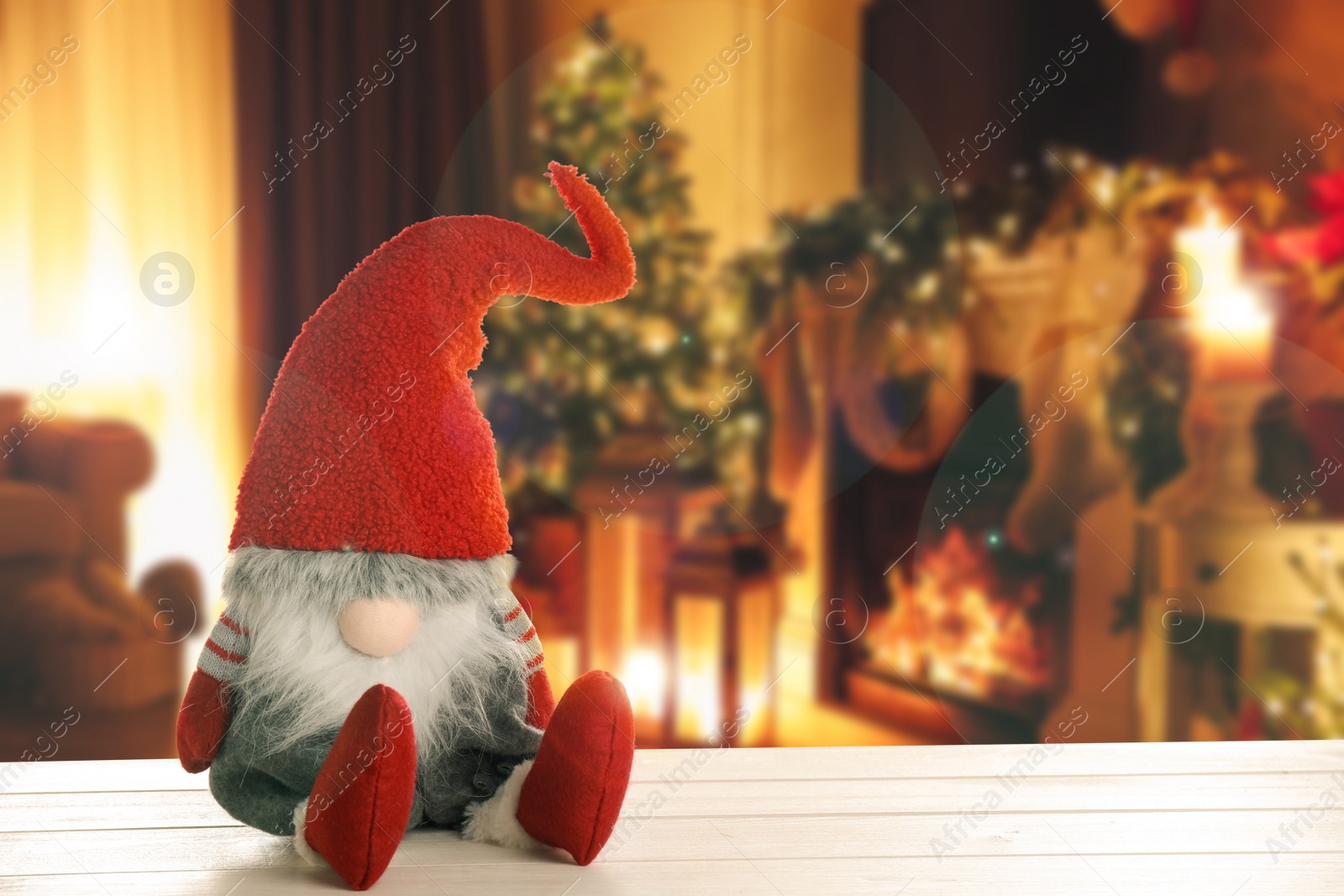 Image of Funny Christmas gnome on white wooden table in room with festive decorations. Space for text