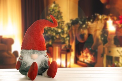 Image of Funny Christmas gnome on white wooden table in room with festive decorations. Space for text