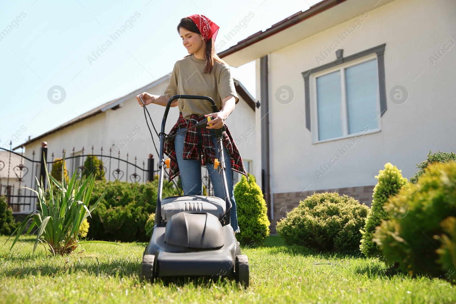 Photo of Smiling woman with modern lawn mower in garden