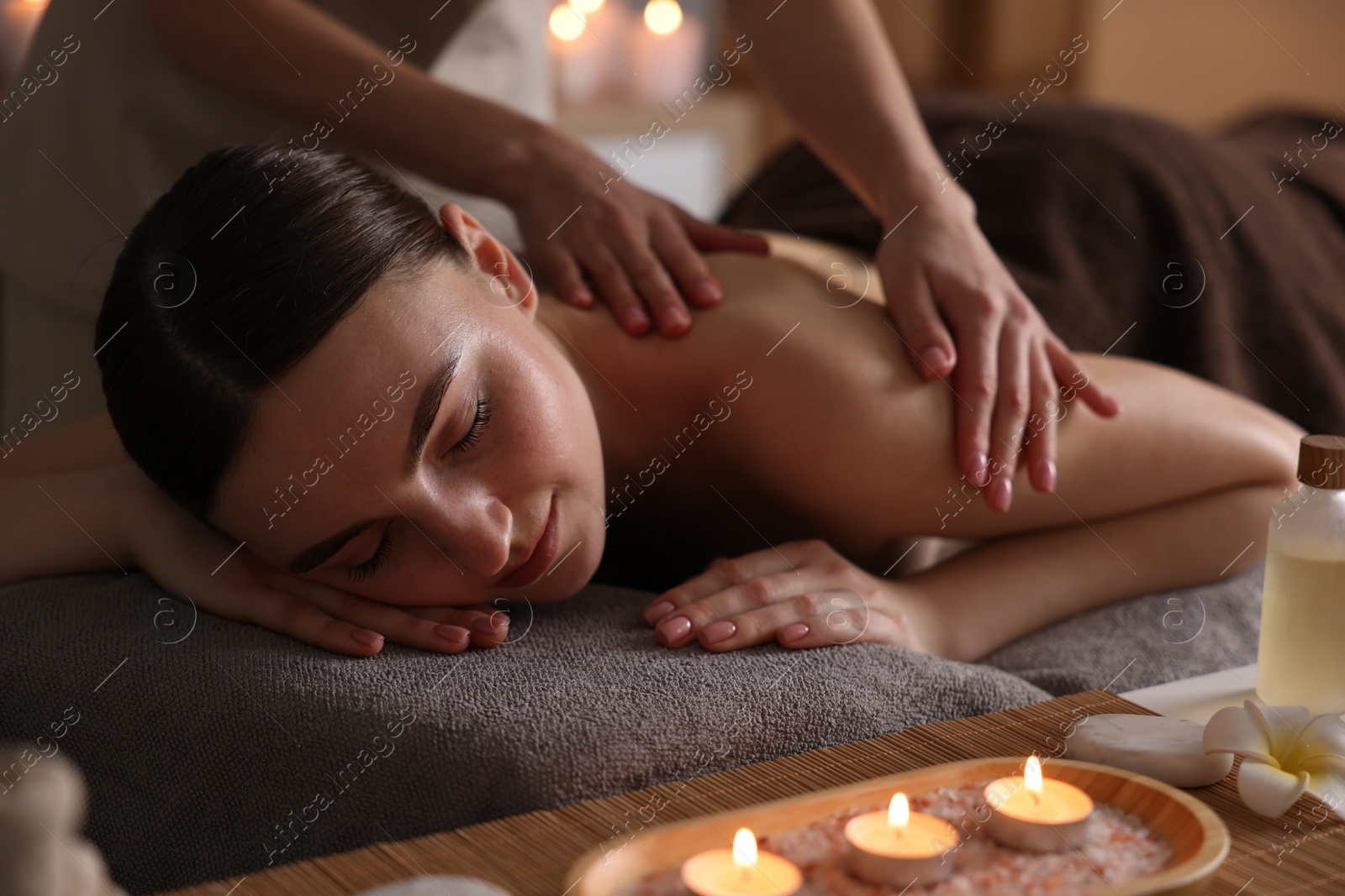 Photo of Spa therapy. Beautiful young woman lying on table during massage in salon