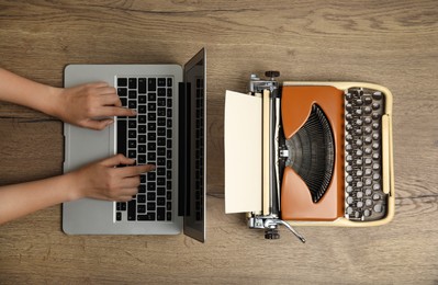 Photo of Woman working with laptop near old typewriter at wooden table, top view. Concept of technology progress