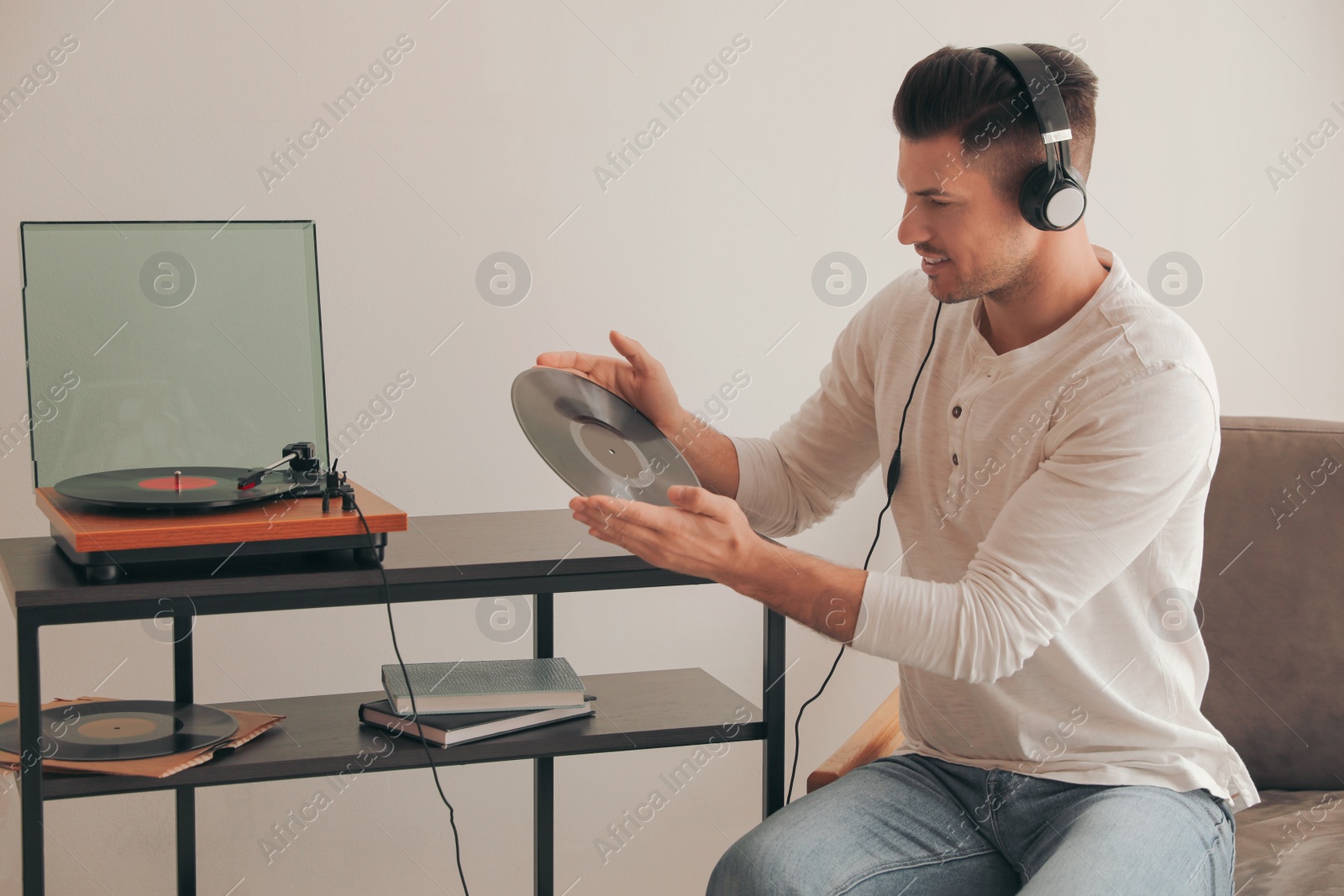 Photo of Happy man listening to music with turntable at home