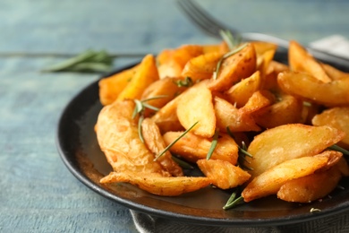 Photo of Plate with baked potatoes and rosemary on table, closeup