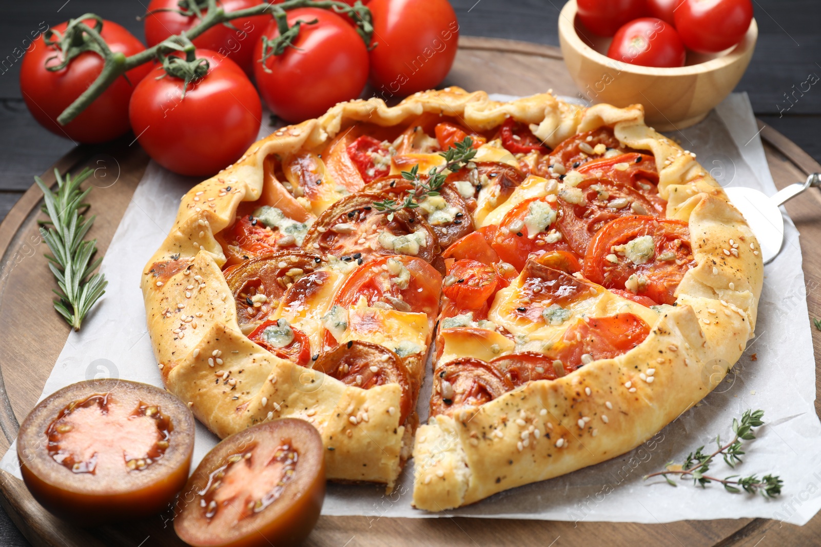 Photo of Tasty galette with tomato and cheese (Caprese galette) on wooden board, closeup