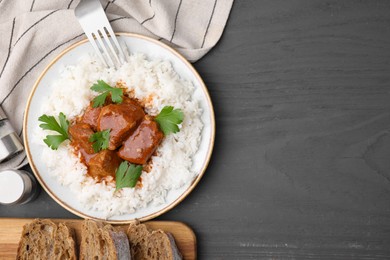 Delicious goulash served with rice on grey wooden table, flat lay. Space for text