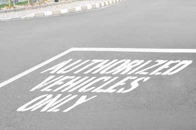 Image of Sign Authorized Vehicles Only painted on asphalt road outdoors