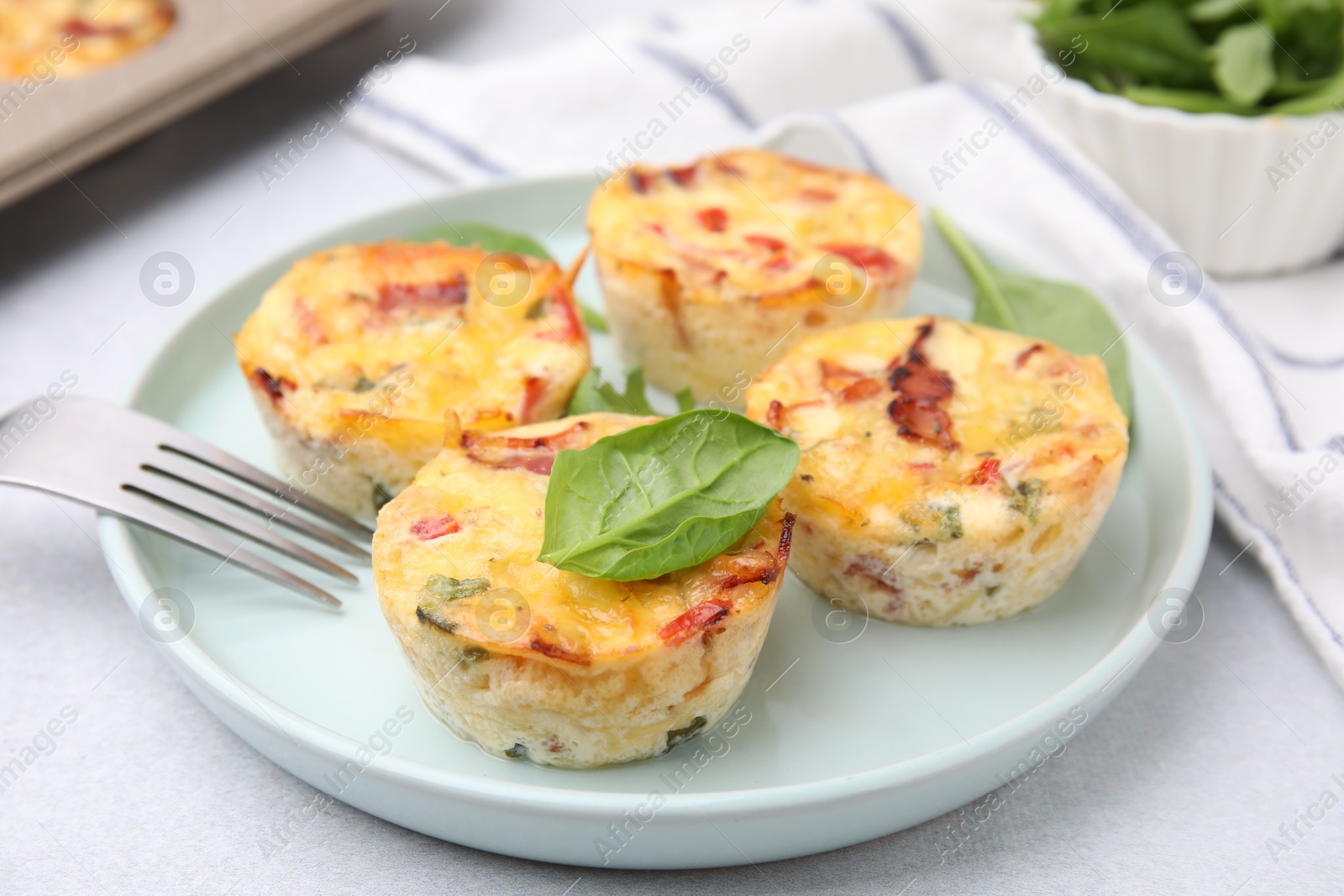 Photo of Freshly baked bacon and egg muffins with cheese served on table, closeup