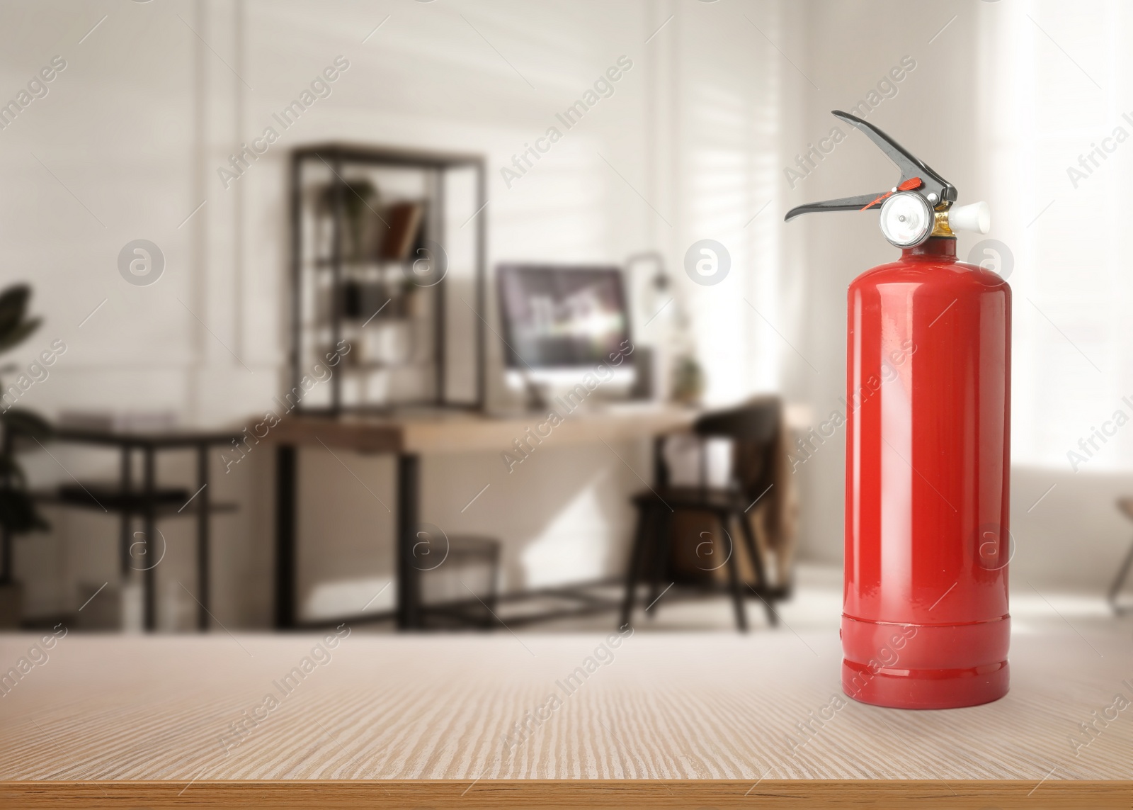 Image of Fire extinguisher on wooden table in office. Space for text