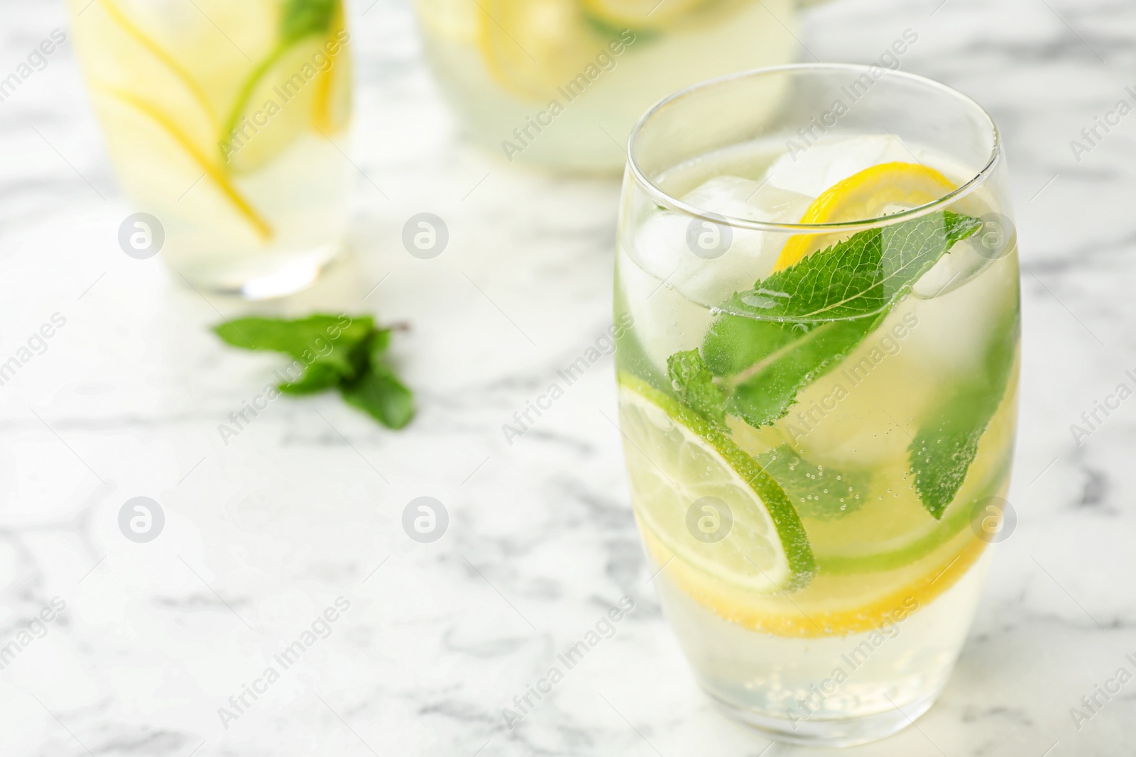 Photo of Glass of refreshing lemonade on marble table, closeup and space for text. Summer drink