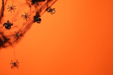 Decorative spiders and web on orange background, flat lay with space for text. Halloween celebration
