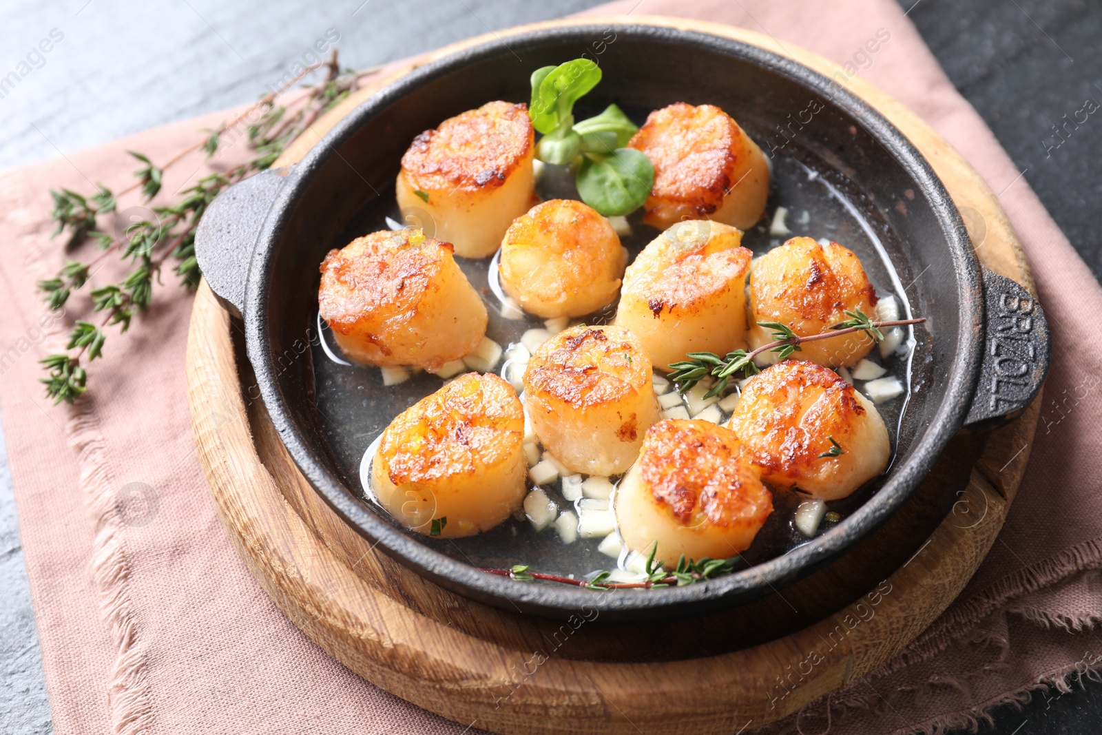 Photo of Delicious fried scallops in dish and thyme on table, closeup