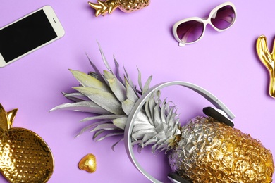 Flat lay composition with pineapple, smartphone, sunglasses and headphones on color background