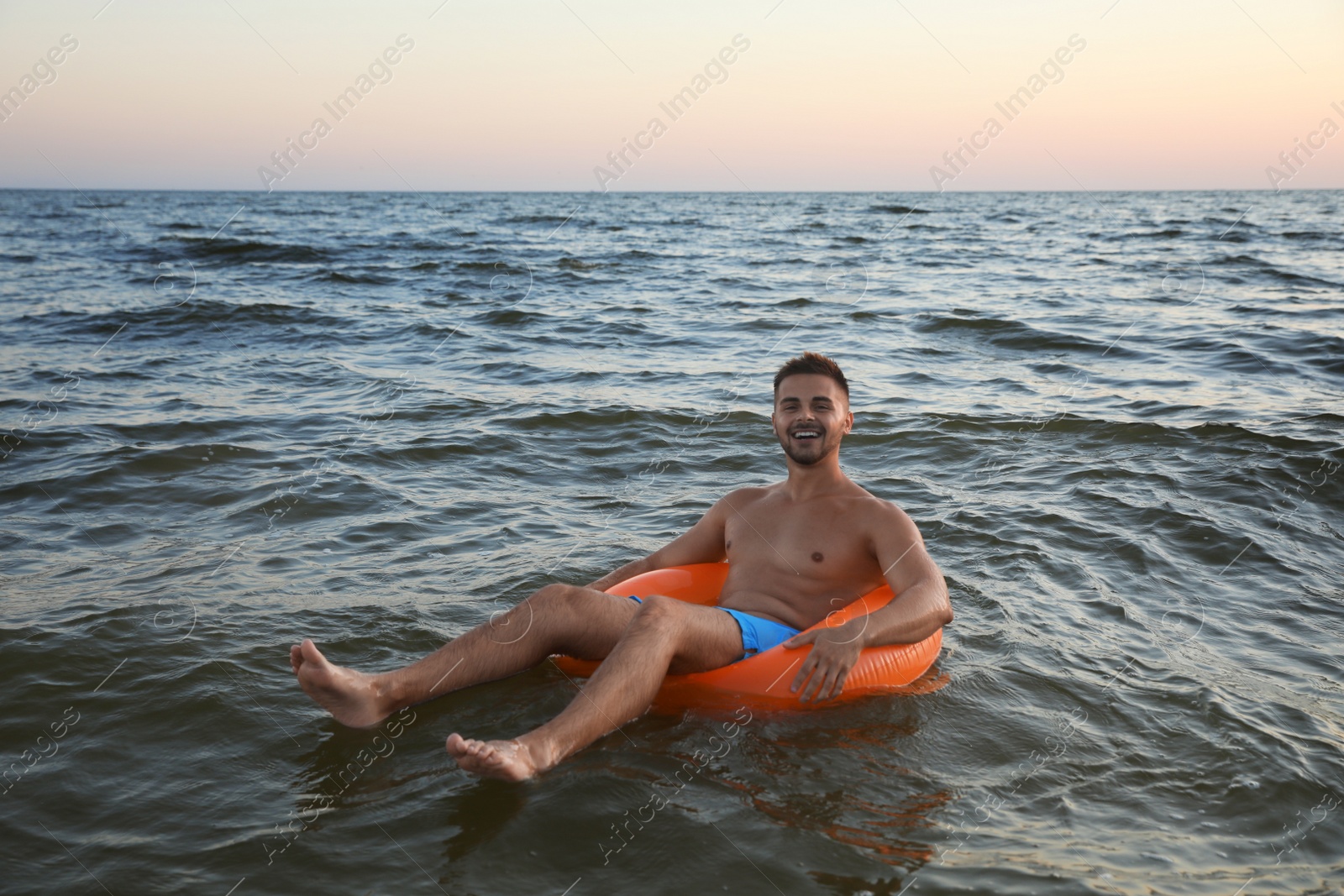 Photo of Happy young man on inflatable ring in water