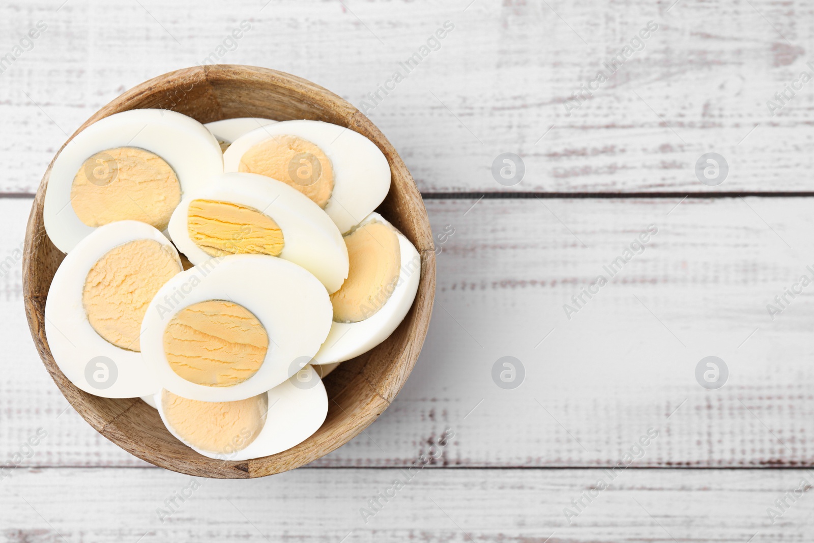 Photo of Bowl of fresh hard boiled eggs on white wooden table, top view. Space for text