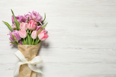 Photo of Beautiful bouquet of colorful tulip flowers on white wooden table, top view. Space for text