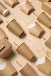 Photo of Eco friendly food packaging. Paper containers and wooden cutlery on beige background, above view