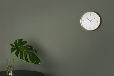 Analog clock on grey wall indoors. Time of day