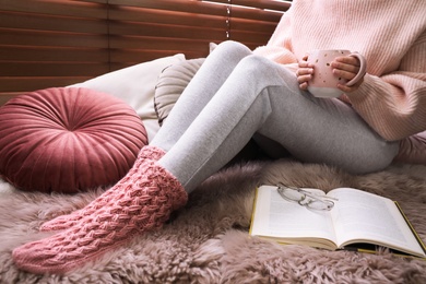 Photo of Woman with cup of hot drink resting at home, closeup