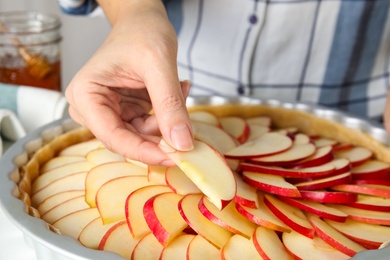 Photo of Woman putting apple slice into baking dish to make traditional English pie, closeup