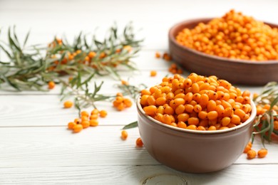 Photo of Fresh ripe sea buckthorn in bowl on white wooden table. Space for text