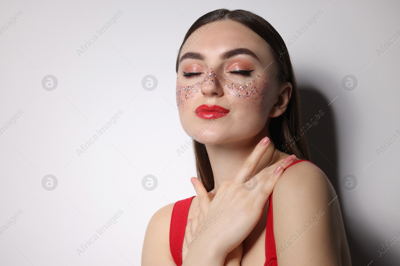 Photo of Beautiful woman with glitter freckles on light background. Space for text