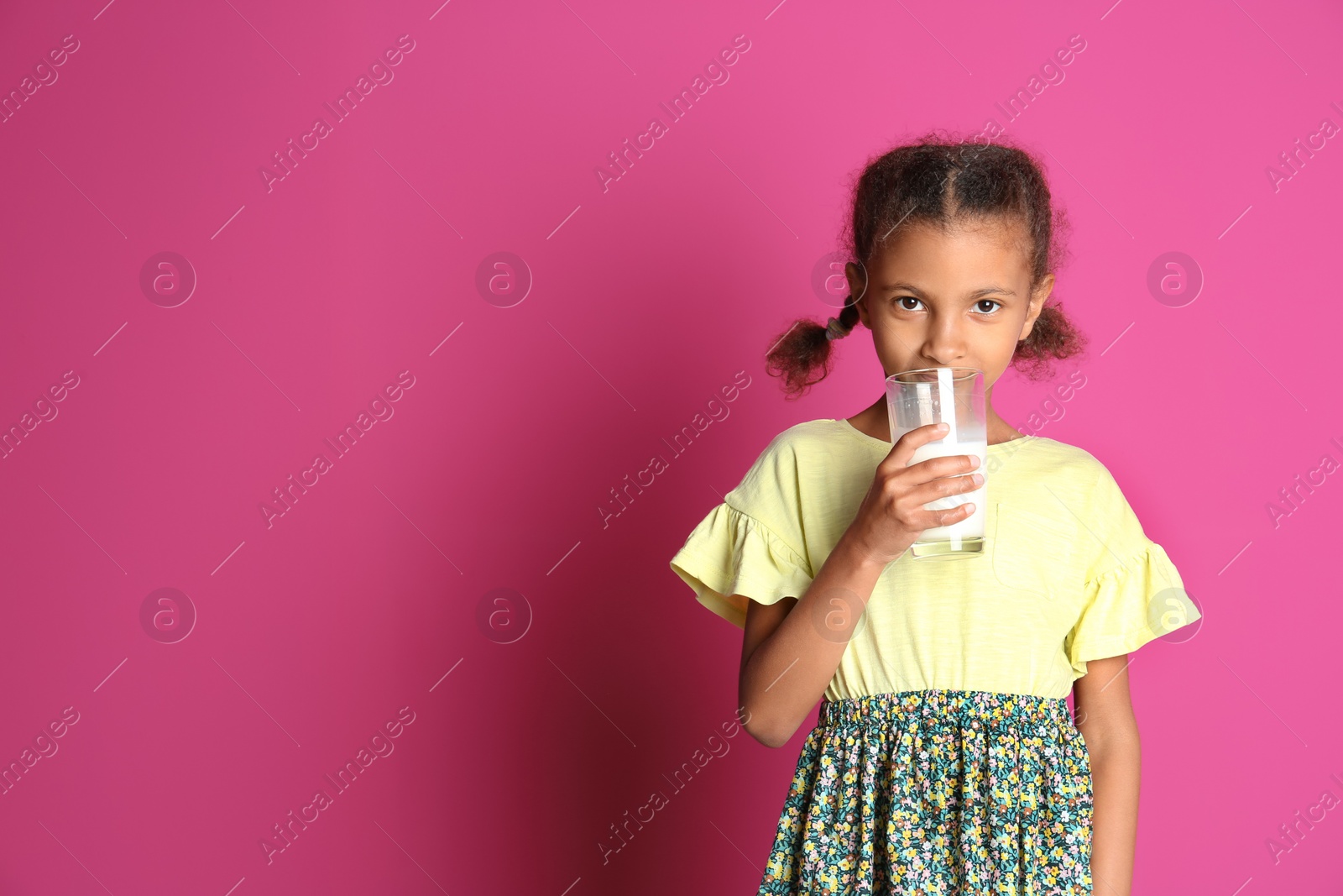 Photo of Adorable African-American girl with glass of milk on color background