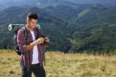 Photo of Tourist with hiking equipment and binoculars in mountains