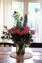 Photo of Beautiful bouquet of roses and napkins on wooden table indoors