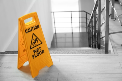 Photo of Safety sign with phrase Caution wet floor near stairs. Cleaning service