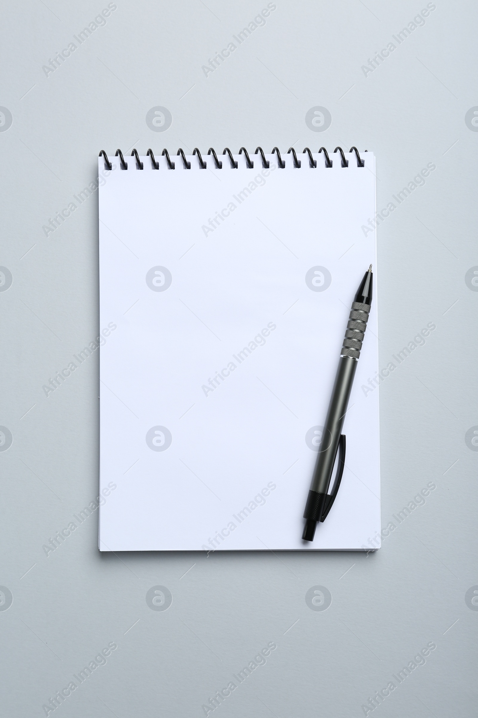 Photo of One notebook and pen on light grey background, top view. Space for text