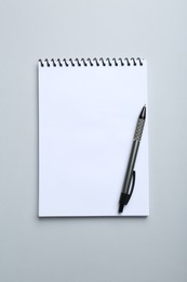 Photo of One notebook and pen on light grey background, top view. Space for text