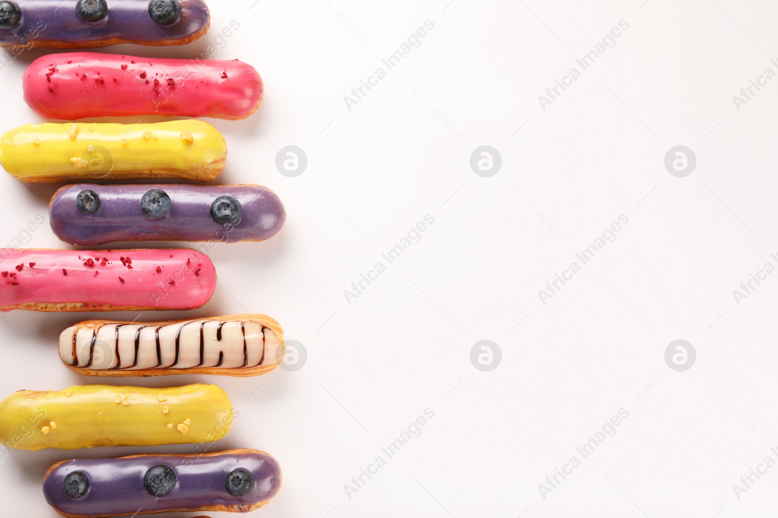 Photo of Delicious eclairs covered with glaze on white background, top view