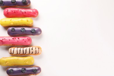 Delicious eclairs covered with glaze on white background, top view