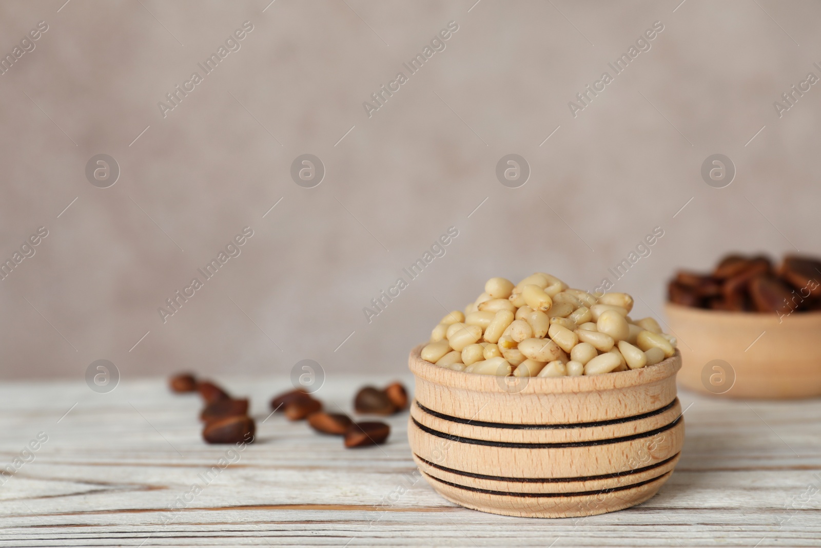Photo of Bowl with pine nuts on wooden table. Space for text
