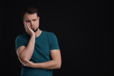 Portrait of sad man on black background, space for text