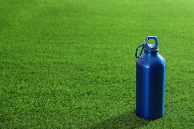 Photo of Bottle of water and space for text on artificial grass. Fitness equipment