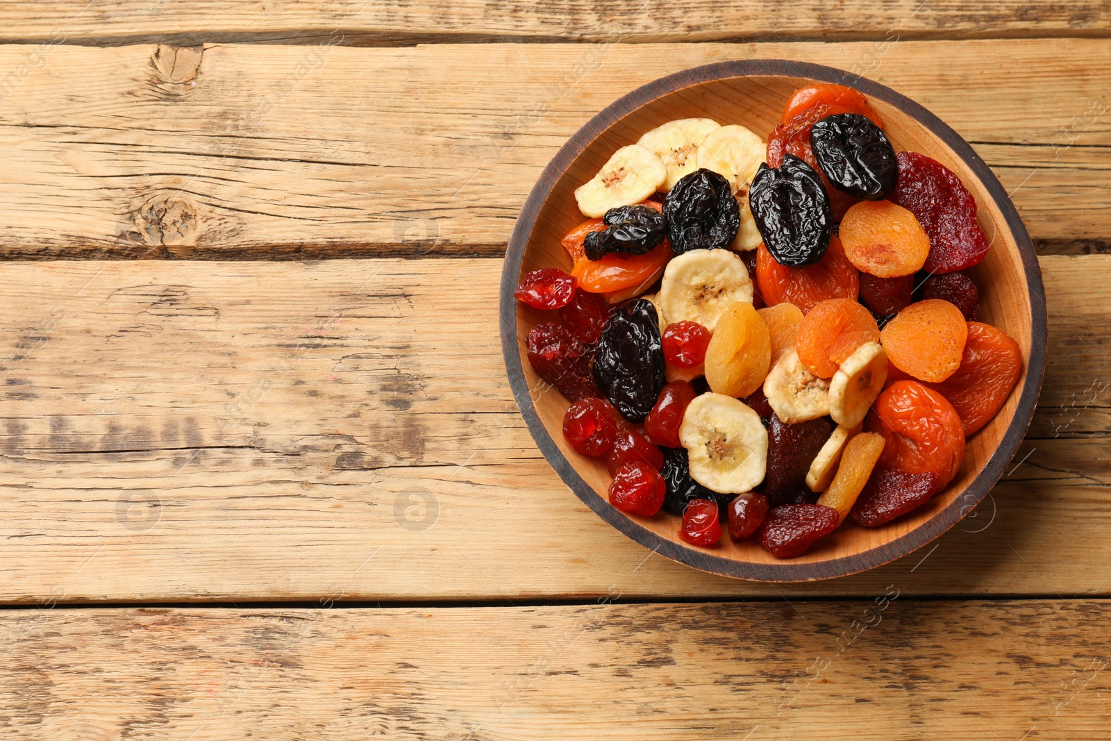 Photo of Mix of delicious dried fruits on wooden table, top view. Space for text