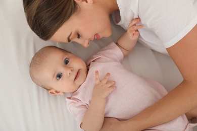 Portrait of mother with her cute baby lying on bed, top view