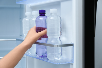 Photo of Woman taking bottle of water from refrigerator, closeup