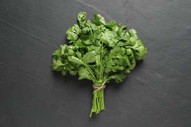 Photo of Bunch of fresh green cilantro on black table, top view
